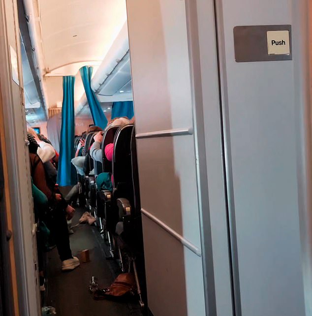 Passengers are seen gripping the backs of seats as the plane rattled due to extreme turbulence