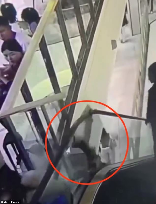 She loses her balance as the escalator starts dragging her down. The woman then desperately tries to grab the handrail as she suddenly falls through a small gap between the stairs and the handrail