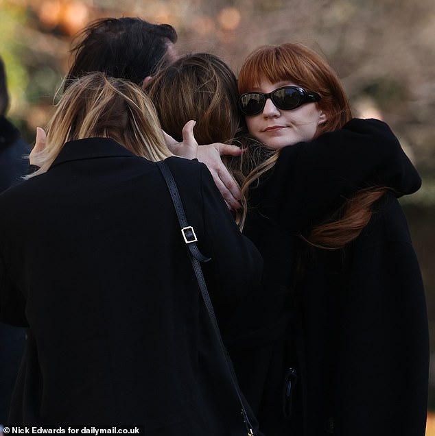 Singer Nicola Roberts, 39, hugs a fellow mourner before the funeral this afternoon