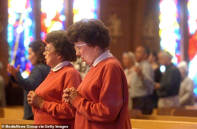 Peggy Coppom, left, and her sister Betty Hoover are seen praying in church in 2005