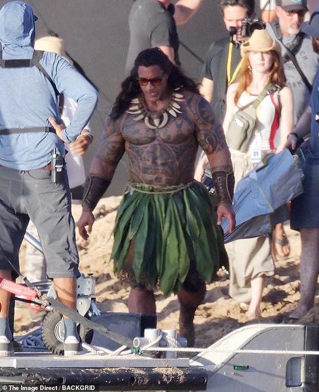 The You're Welcome singer - known for his signature bald head - wore a flowing raven wig and a bone necklace - topped off with shades between takes as he strolled around in character Maui