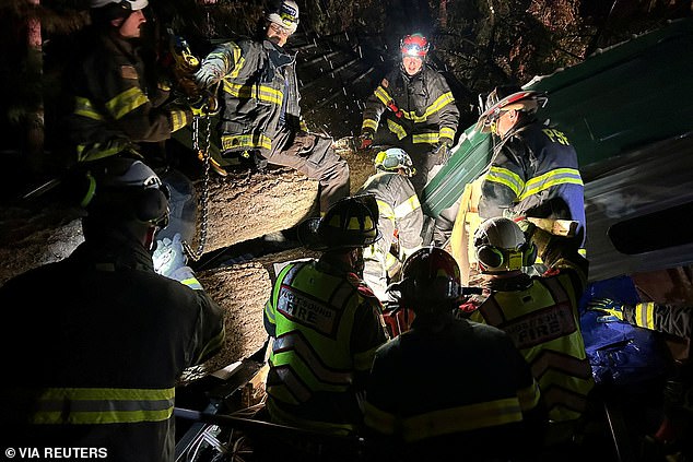 Firefighters and paramedics respond after a tree fell on a trailer Tuesday in Maple Valley, Washington, trapping two people inside