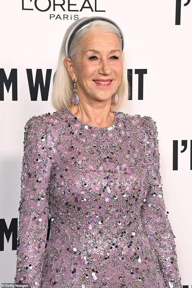 A pair of purple jeweled earrings almost touched the top of her shoulders as she posed on the red carpet