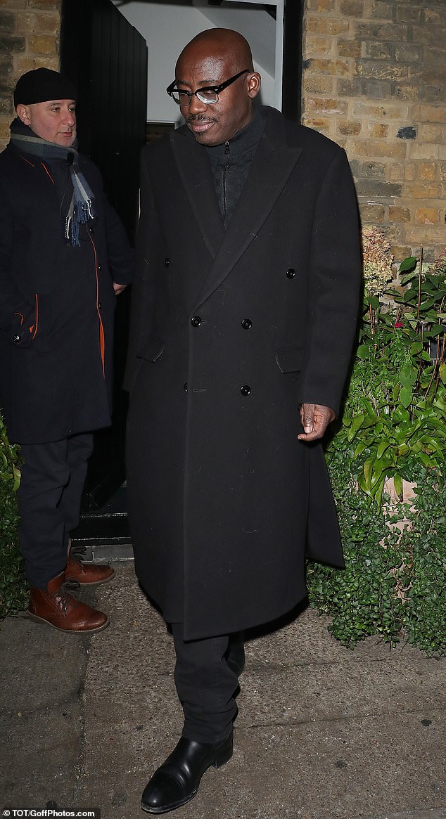 Former British Vogue editor Edward Enninful, wearing a black knee-length coat, along with matching trousers and boots