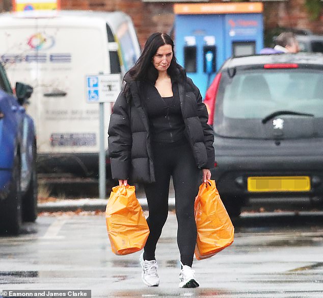 The WAG wrapped herself up warm from the cold and rainy weather in a cozy black puffer coat and let her brunette locks fall loose around her shoulders