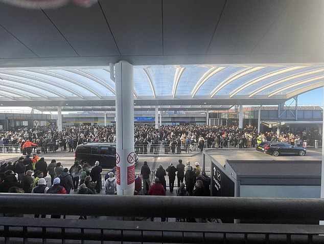 Passengers stand outside Gatwick Airport's South Terminal in the freezing cold after yesterday's security alarm