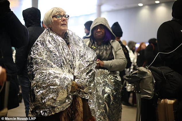 Passengers in foil blankets stand outside Gatwick's South Terminal on Friday after a suspicious piece of luggage triggered a security alert