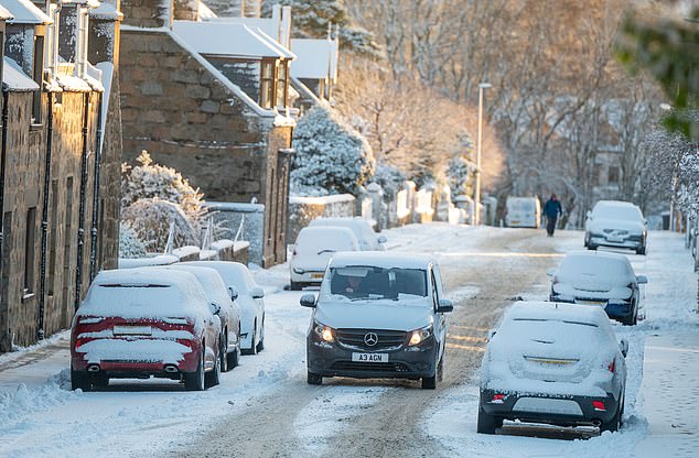 Cars are pictured driving through the snow on the A97 near Huntly, Aberdeenshire this morning