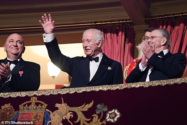 Charles is shown smiling and waving to the crowd at the Royal Albert Hall