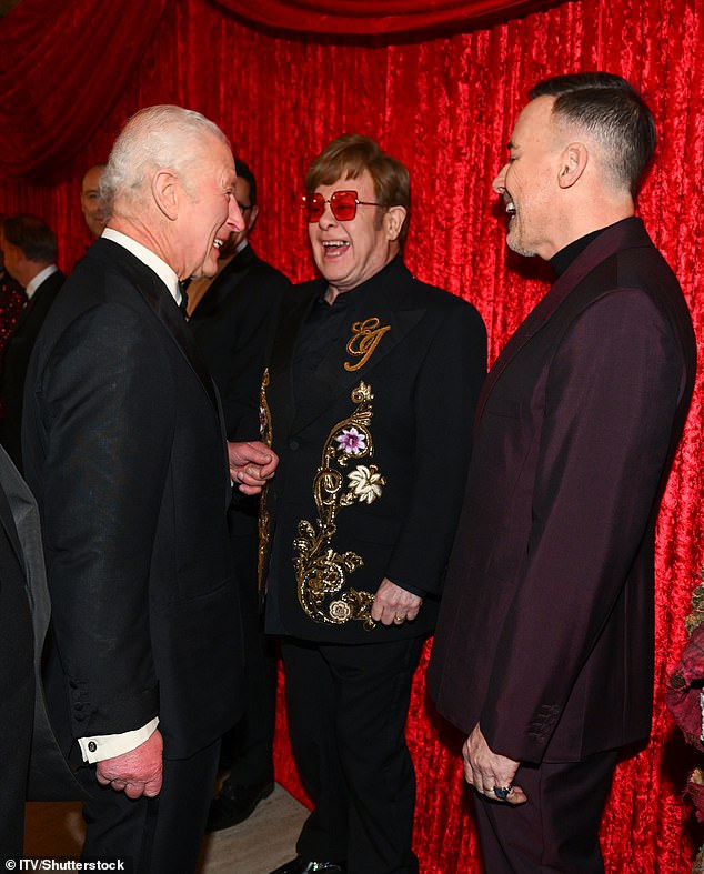 Elton John and David Furnish smile as they meet the monarch after greeting him