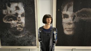 The Ai-Da robot stands in front of her 'AI God' painting on Alan Turing