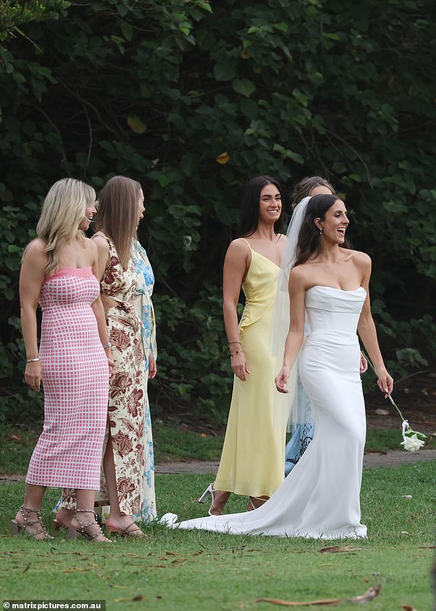 Emily struck a sultry pose as she took photos with her bridesmaids, letting her dark locks tumble down her back in loose waves as she held a single white rose