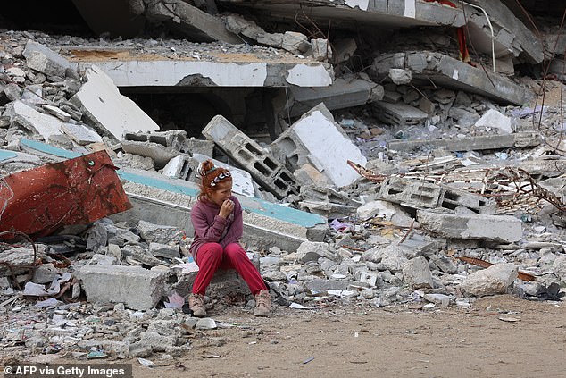 A Palestinian girl rests on the rubble of a destroyed building west of Gaza City, November 25, 2024