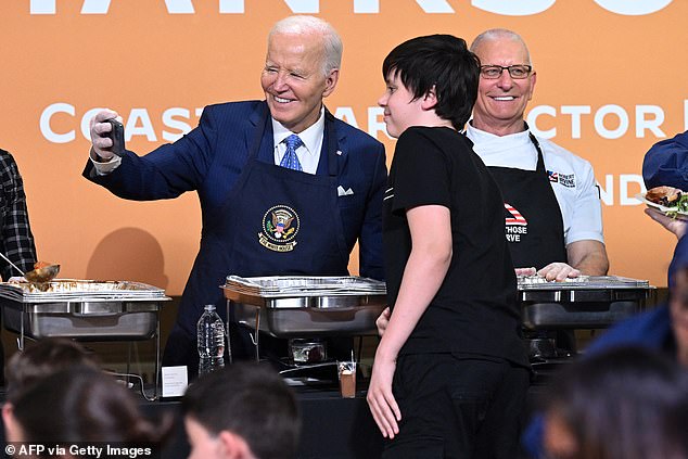 President Joe Biden takes a selfie while working a food line during a 'Friendsgiving' dinner for Coast Guard families on Staten Island Monday night