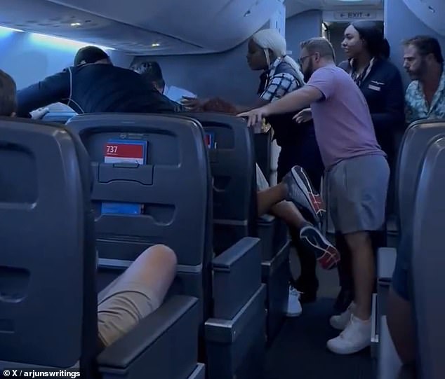 The passengers were seen shouting at the passenger to take his hands off the woman sitting next to him, while a female flight attendant tried to mediate