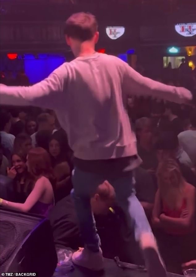 The man gets to his feet and is still looking down and away from the stage when the rapper kicks him in the head