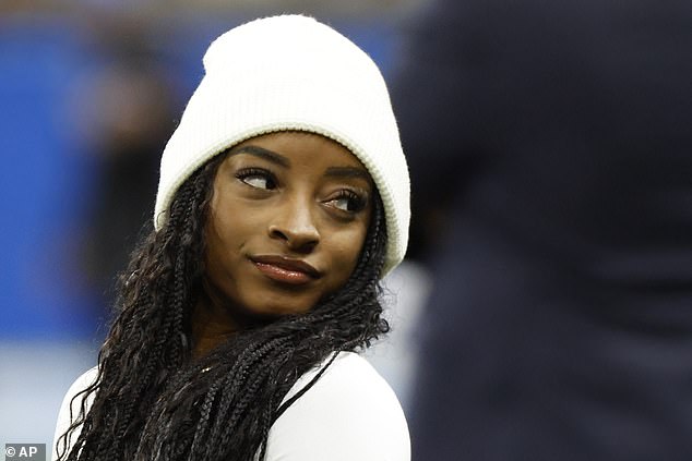 Biles poses for photographers at the edge of the field as she bundles up against the Detroit cold