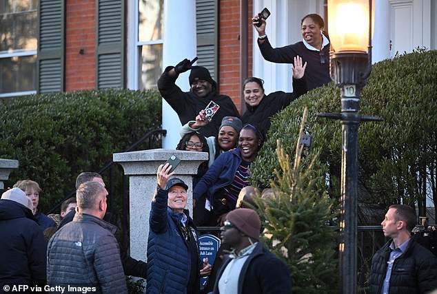 Biden poses for a selfie as onlookers watch as he wandered through the stores