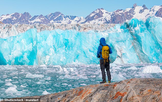 A male hiker looks at a huge glacier near Kulusuk, Greenland