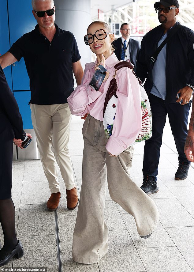 Ariana arrived dressed to impress on her flight, showing off a touch of boho chic in bone-colored flared trousers. She dressed in large, square-framed glasses, which further dwarfed her already petite face