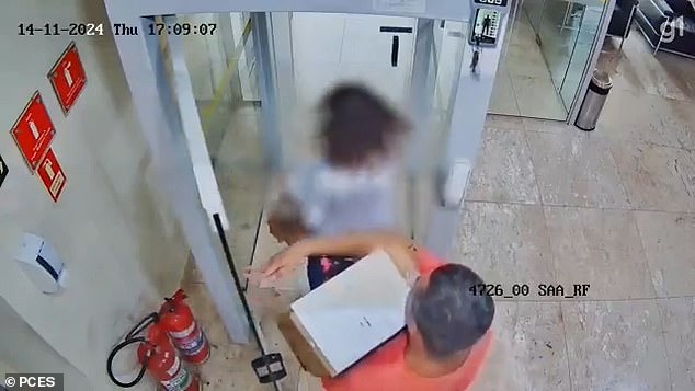 Eduardo Oliveira carries a box full of the money he stole from a branch of the Banco do Brasil where he worked in Vitória, Brazil, as he followed his wife out the door on November 14.