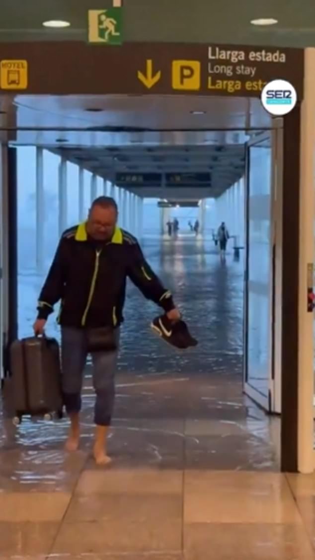 A man is seen taking off his shoes and wading through the departure lounge of El Prat airport