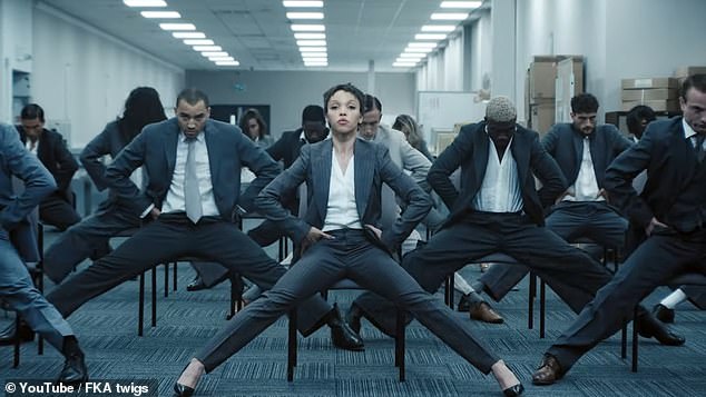 The singer and a team of dancers started in an office setting, fully dressed in matching blue suits