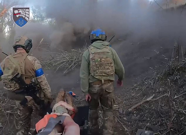 Incredible new image from the front line shows brave Ukrainian soldiers carrying a wounded comrade on a stretcher through Russian gunfire without hesitating