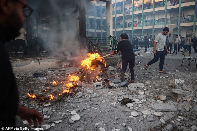 A displaced Palestinian youth tries to control a fire under the rubble after an Israeli attack on a UN-run school where people had taken refuge, in the Nusseirat refugee camp in the central Gaza Strip on November 20, 2024