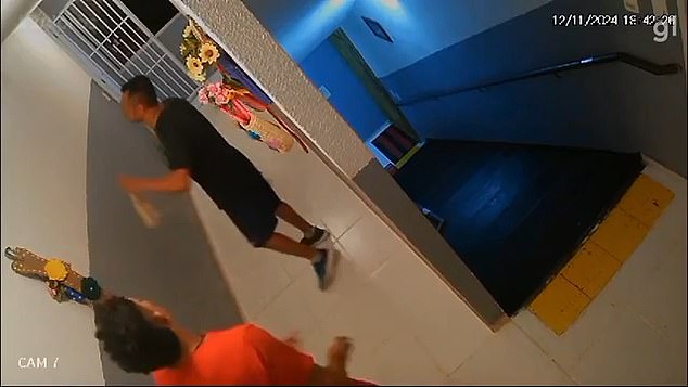 Building manager Jacó Pereira is seen here placing a Christmas decoration on the wall after a tenant (pictured in the orange shirt) became angry with an elderly neighbor for putting up decorations in the building