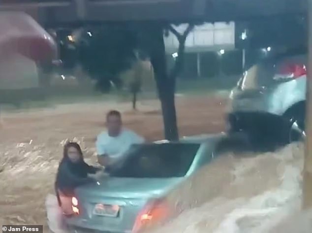 Video footage taken from the city around 1 a.m. shows the 28-year-old influencer grabbing a silver car as waist-deep water flows around her and her husband