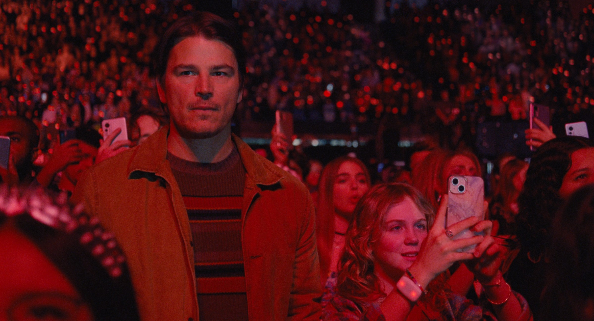 Serial killer Cooper (Josh Hartnett) looks pensive as he stands under dim red lights in a huge crowd during a concert at M. Night Shyamalan's Trap