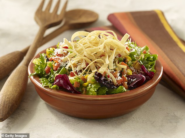 Pictured: A bowl of mixed green vegetable salad, topped with tortilla strips