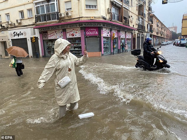 A woman takes a photo of a flooded street in Malaga, Andalusia, Spain, November 13, 2024