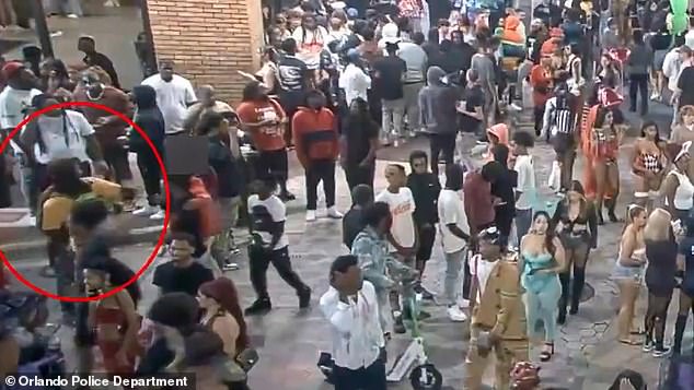 Shocking footage released by police shows the suspect in a yellow shirt walking calmly through the crowd of Halloween revelers before turning and firing his gun