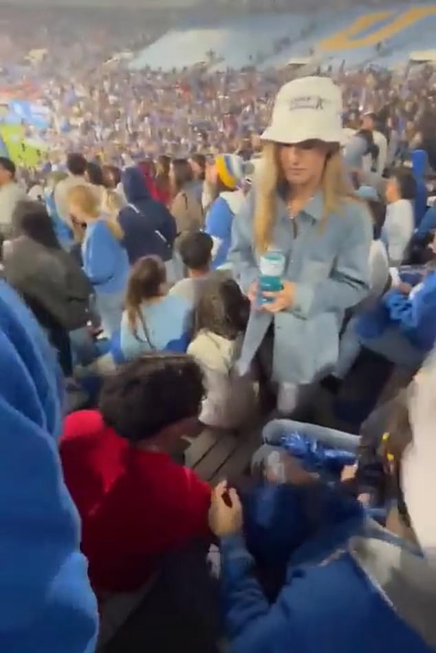 This woman in a hat punched the man in a red sweatshirt during a college football game