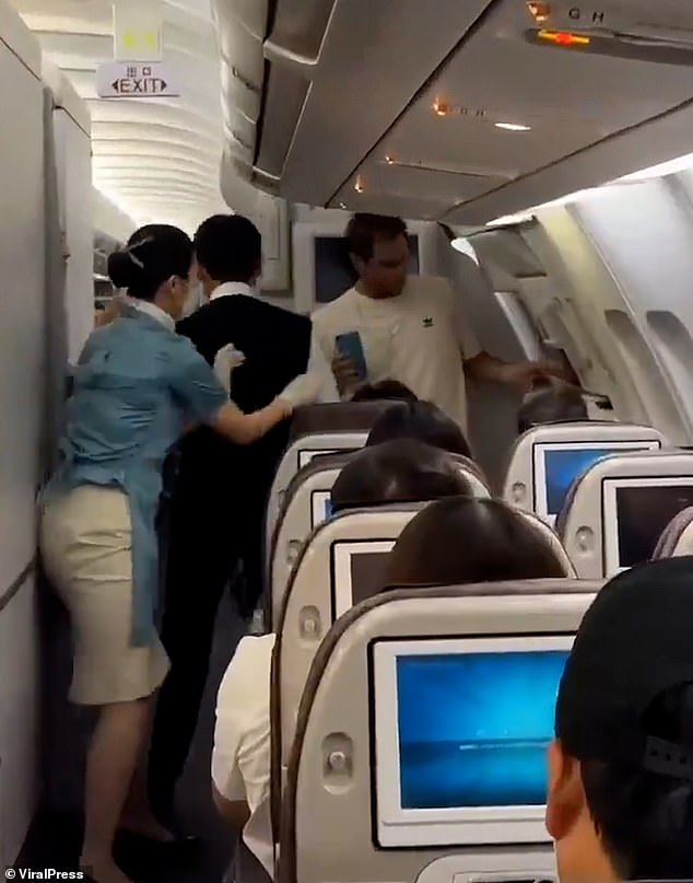 A flight attendant goes to restrain the man, who allegedly threatened one of the crew members after sitting in their seat