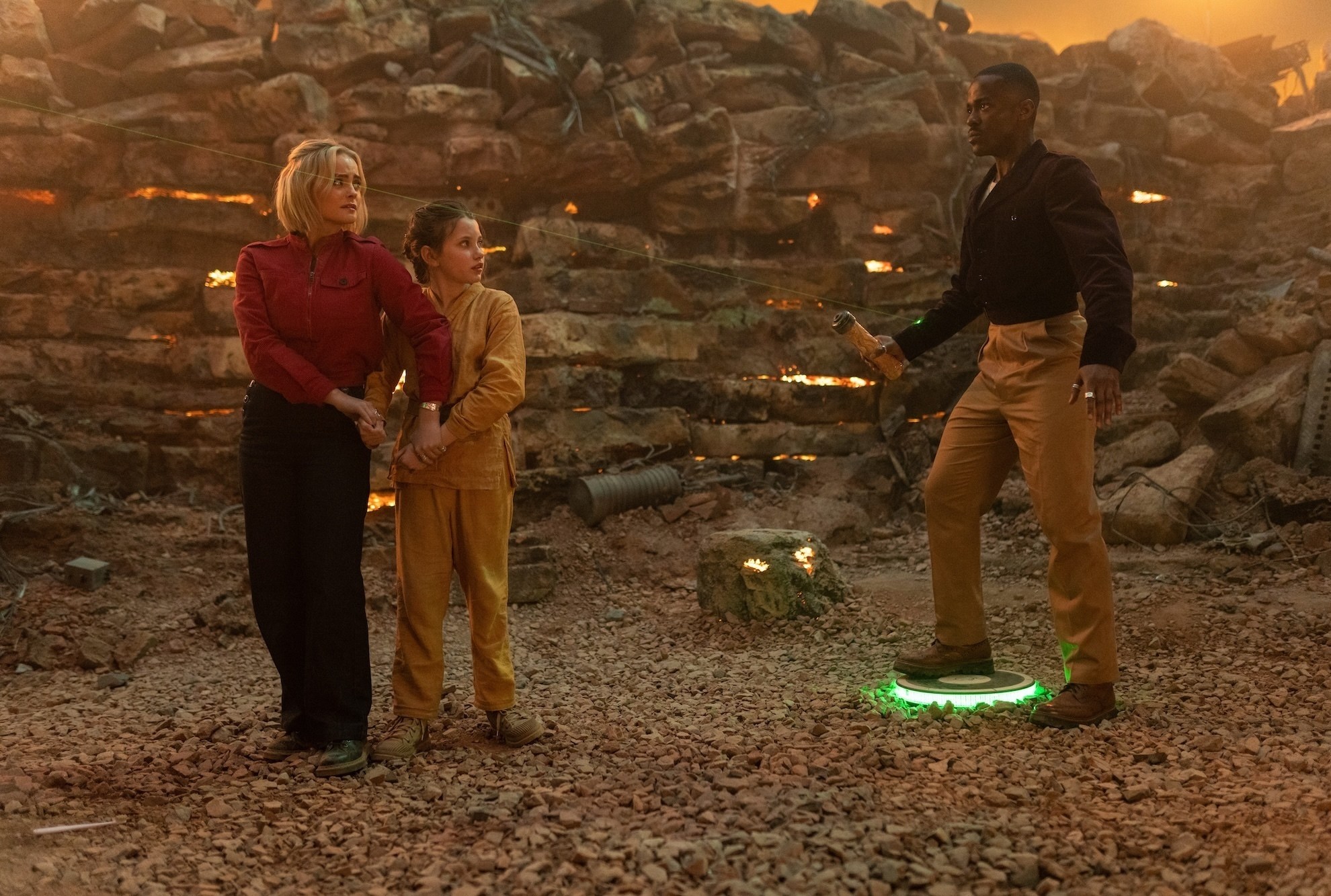 The Doctor stands on a landmine that is greenlit as Ruby Sunday and a little girl stand nervously in front of him in the Doctor Who episode 