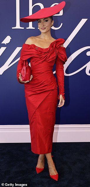 Meanwhile, model Olivia Molly Rogers, 32, wore a bright red long-sleeved strapless maxi dress with a clutch and pointy slingback heels