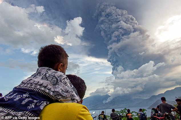 Residents watch the eruption of Mount Lewotobi Laki Laki from the village of Eputobi