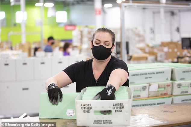 Above, a woman is seen wearing a face mask at a postal voting center in Phoeniz, Arizona, during the 2020 presidential election