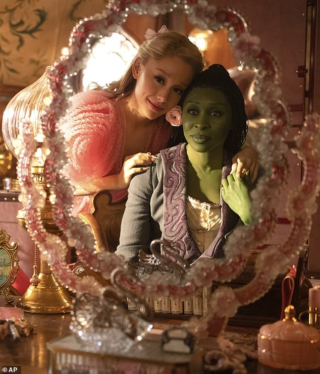 As Elphaba (Cynthia) breaks down in the Ozdust Ballroom after being isolated due to her green skin and tears run down her cheeks, former enemy Glinda (Ariana) takes her head in her hands