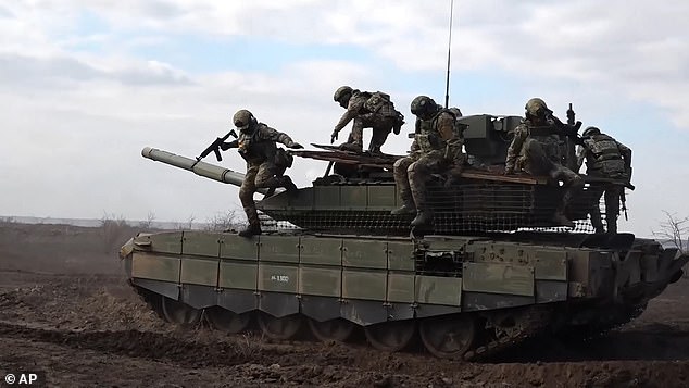 Russian soldiers jump from a T-90M Proryv tank during combat training for assault units at a secret location