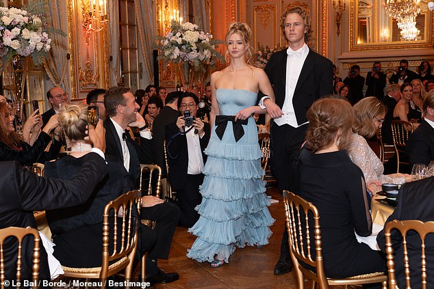 Leo and Apple crossed their arms as they entered the luxurious ballroom before blowing a kiss to her proud dad Chris