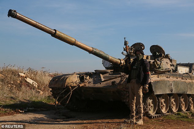 A rebel fighter holds his weapon as he stands in front of a military vehicle in Menagh, north of Aleppo, Syria, December 2