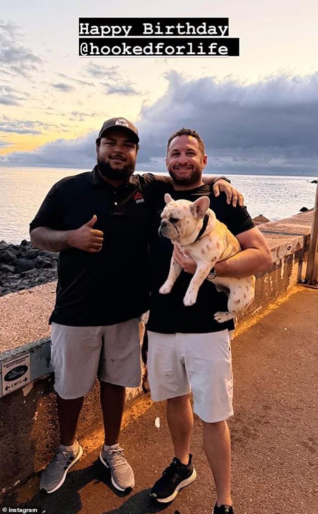 The last photo he shared was in August, when he posed next to his partner on a sidewalk with a rocky beach and a sunset behind them