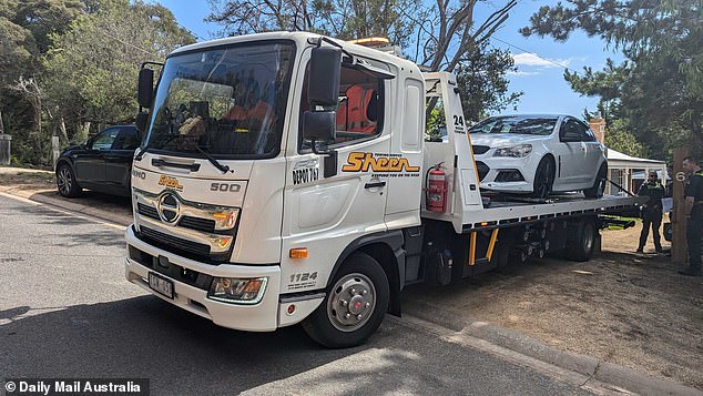 A white tow truck arrived to tow away a white Holden parked on the property