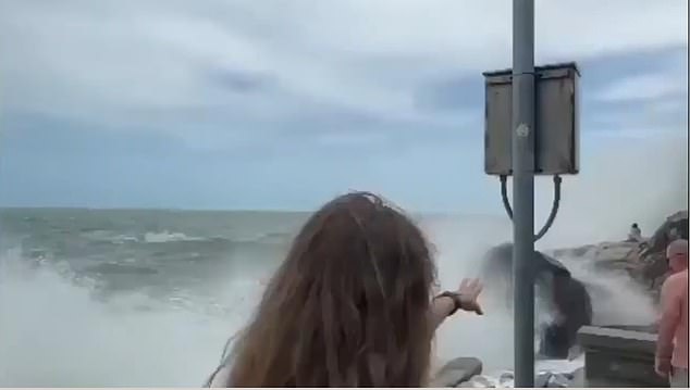 A woman is seen stretching out her arm as the waves crash around Kamilla, with no one around to help her