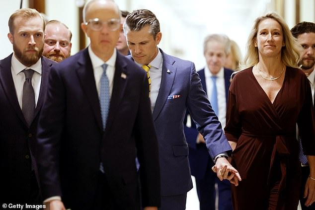 Hegseth walks hand in hand with his wife Jennifer as he leaves Senate meetings