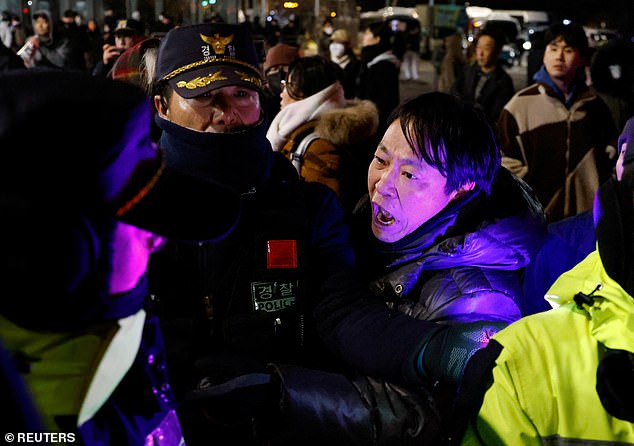 A man confronts police officers outside the National Assembly after South Korean President Yoon Suk Yeol declares martial law in Seoul